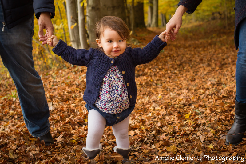 fall_mini_session_baby_photoshooting_zurich_berg_family_photographer_amelie_clements_photography_baby_girl_walking_hands_parents_forest