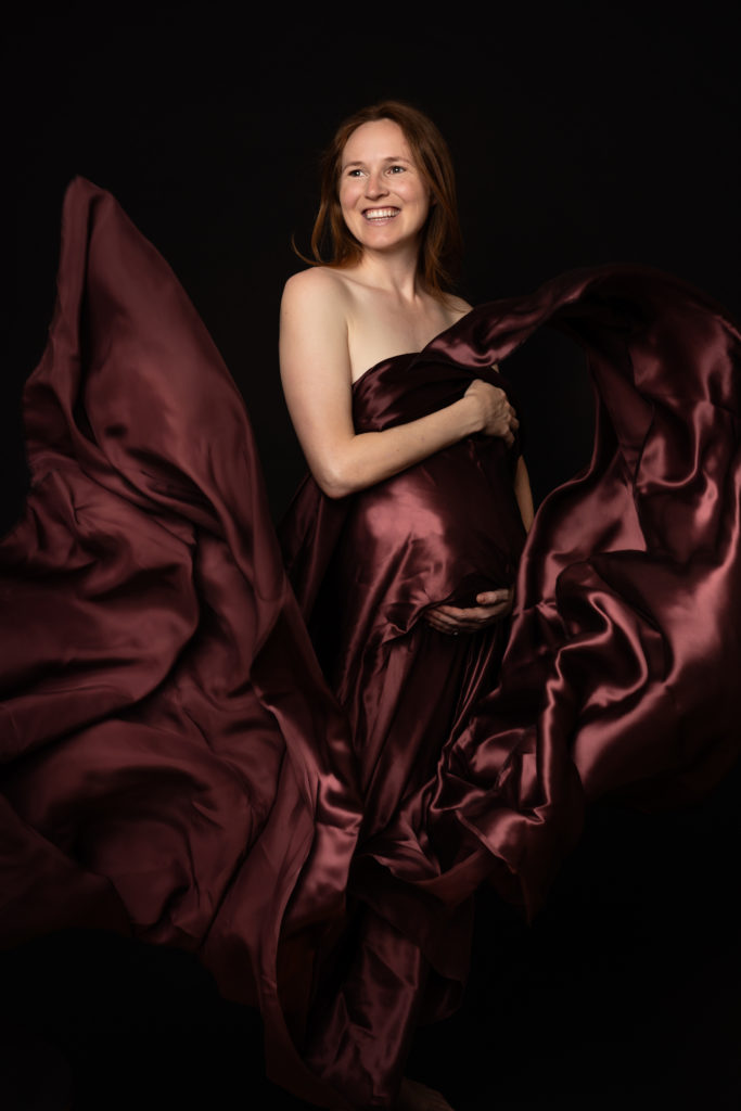 pregnancy photographer zurich elegant maternity portrait red silk veil flying Amelie Clements photostudio