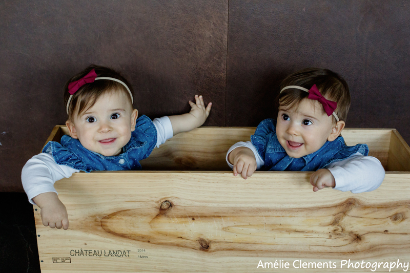 baby-photographer-zurich-horgen-twins-switzerland-amelie-clements-baby-girls-9month-old-sit-wine-box-smile-on-location-home