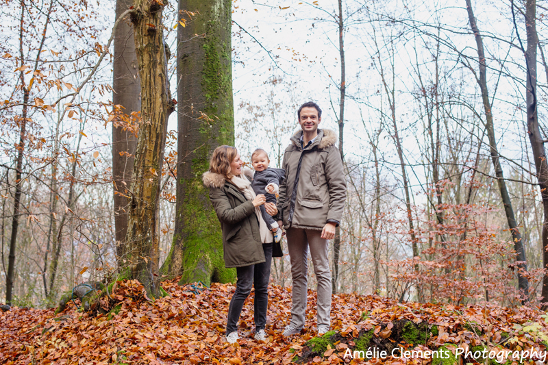 family-photographer-zurich-baby-switzerland-winter-forest-photosession-amelie-clements-photography-baby-boy-carry-by-parents-woods-autumn-colors-trees